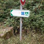 No-entry sign and cycle route marker on an overgrown path